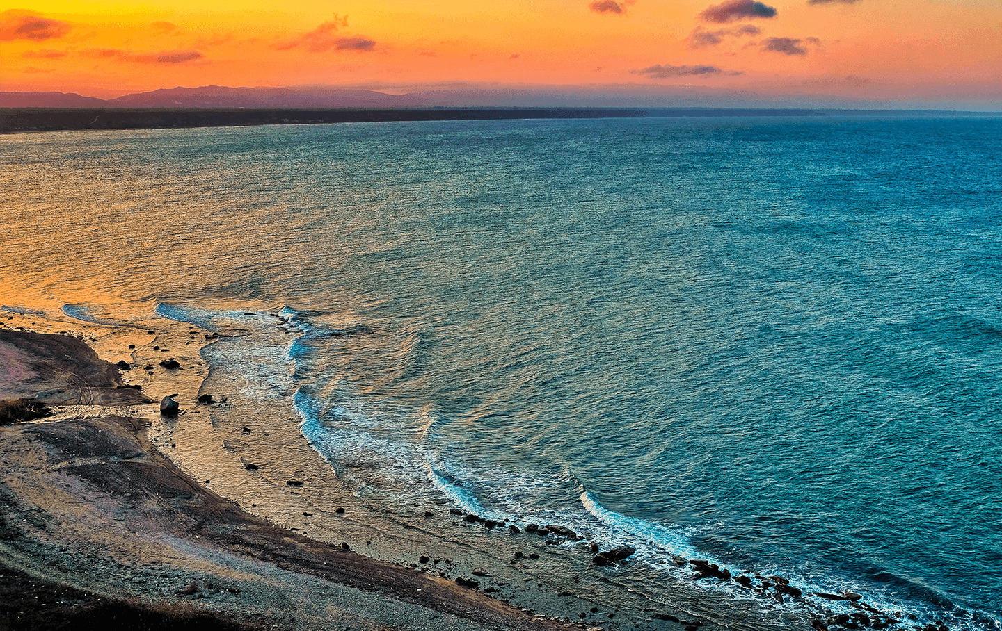 Безмятежный пляж на побережье Каспийского моря с ярко-синими водами и песчаными дюнами.